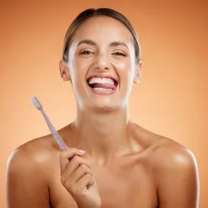 Smiling woman holding a toothbrush, bright white teeth